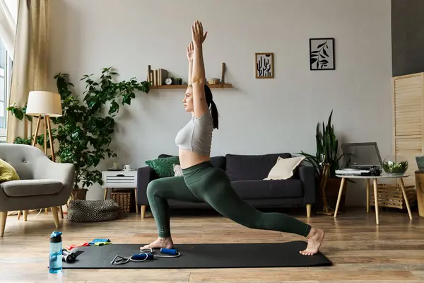 A young woman practices a yoga pose in active wear in her cozy living room, focusing on fitness and balance. — Stock Photo
