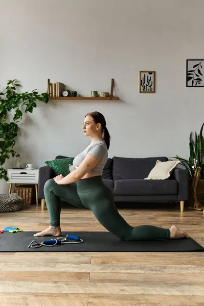 Una donna sportiva si allunga con grazia nel suo salotto, godendo di una routine di allenamento equilibrata in abbigliamento comodo. — Foto stock