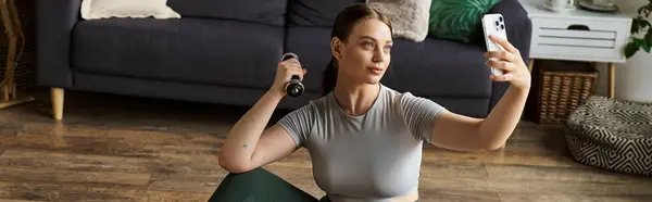 A young woman in stylish active wear engages in a home workout while taking a selfie for motivation. — Stock Photo