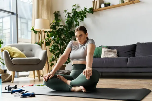 Una mujer deportiva se dedica a un entrenamiento en casa, practicando yoga mientras se centra en su rutina de ejercicios. - foto de stock