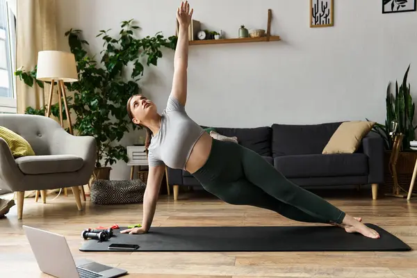 A dedicated woman in active wear focuses on her side plank workout, bringing energy to her home routine. — Stock Photo