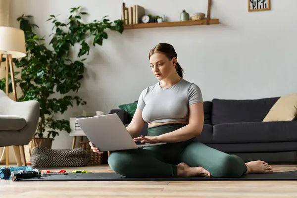 A sportive woman wearing a crop top and leggings exercises at home, focusing on her workout routine. — Stock Photo