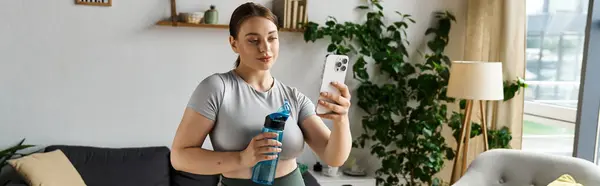 A young, sportive woman in active wear captures a selfie during her home workout in a cozy living room. — Stock Photo