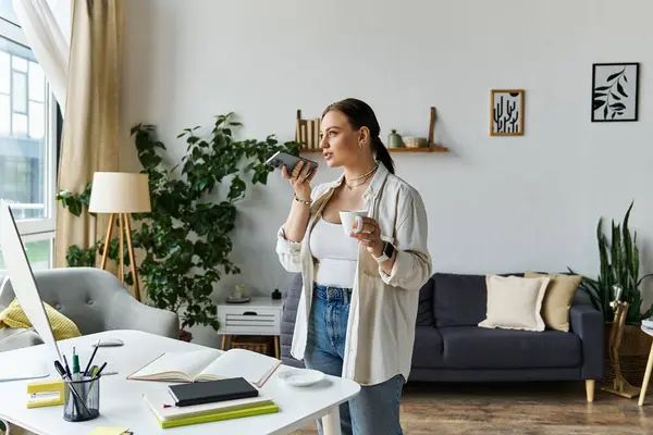 Eine junge Frau in Freizeitkleidung arbeitet von zu Hause aus und nippt an einem Kaffee, umgeben von gemütlichen Pflanzen. — Stockfoto