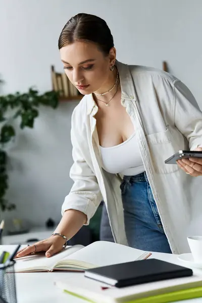 A young woman in casual attire organizes her workspace while working on a computer at home. — Stock Photo