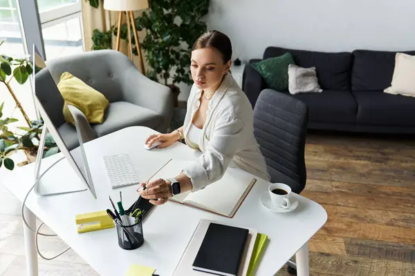 A young woman focused on her tasks at a modern desk with a computer, surrounded by a serene home environment. — Stock Photo