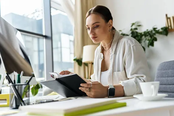 A young woman immersed in her work, reviewing her notes while seated at her home office desk. — Stock Photo