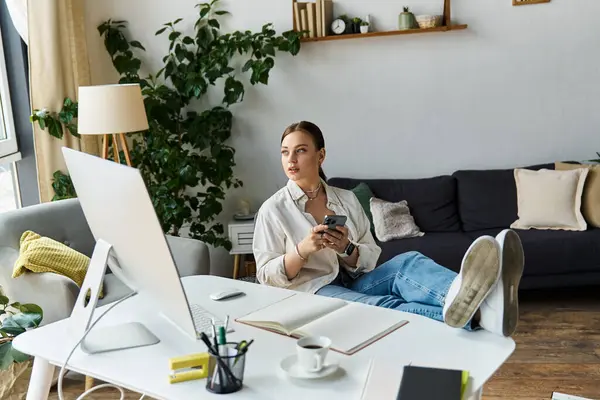 A young woman casually works from home, balancing her tasks while enjoying her comfortable space. — Stock Photo
