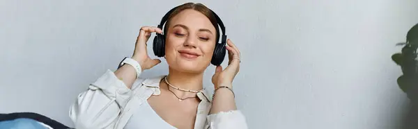 A young woman relaxes in her casual attire, smiling as she listens to music — Stock Photo