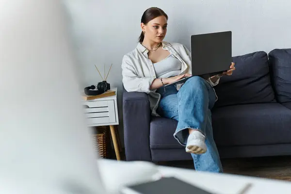Amidst a cozy home setting, a young woman works intently on her laptop, embodying remote productivity. — Stock Photo
