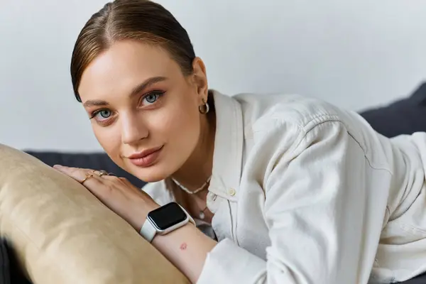 Une jeune femme en tenue décontractée couchée confortablement sur le canapé et regardant la caméra — Photo de stock