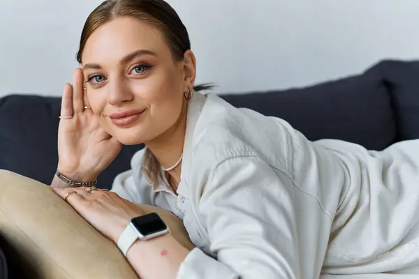 Eine junge Frau sitzt zu Hause, lächelt und blickt in die Kamera — Stockfoto