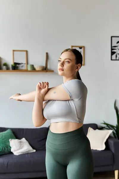 A dedicated young woman in activewear engching exercises at home, promoting fitness and well-being. — стоковое фото