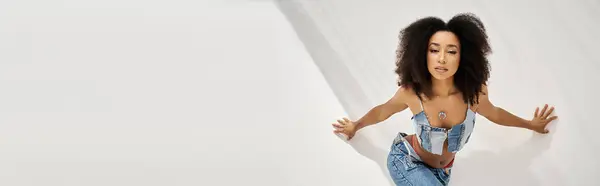 A young woman poses elegantly in bright light, showcasing her fashionable outfit. — Stock Photo