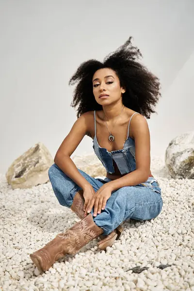 A beautiful young woman showcases her fashion sense in a relaxed pose on soft pebbles. — Stock Photo