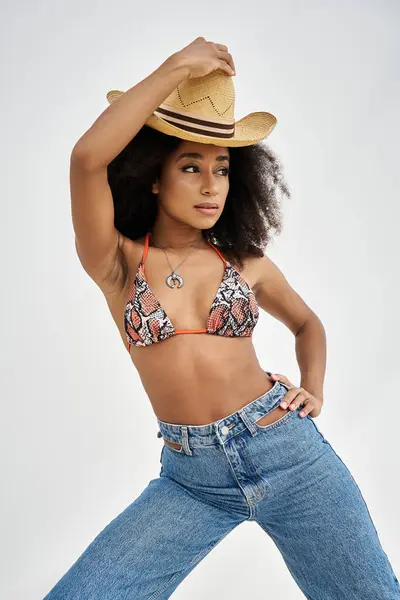 A young woman displays her trendy beach style, confidently posing with a straw hat. — Stock Photo