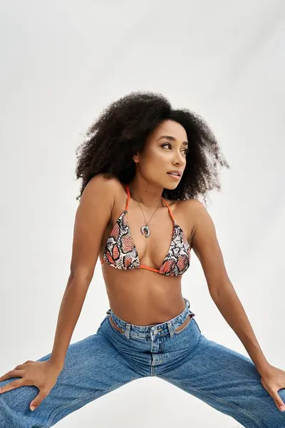 A confident african american woman radiates beauty in stylish swimwear against a light background. — Stock Photo