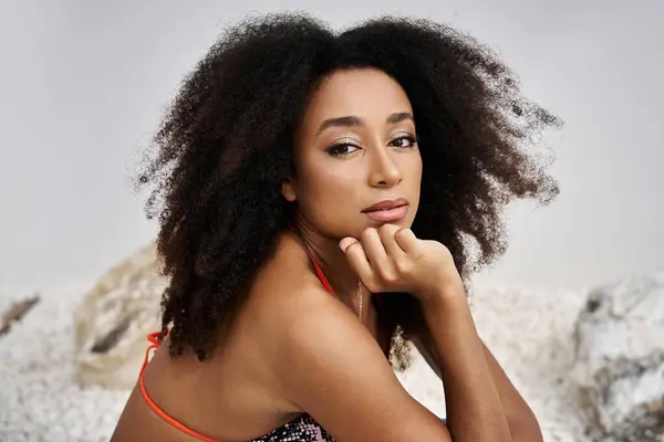 Una hermosa joven con elegante atuendo posa pensativamente sobre un sereno telón de fondo. - foto de stock