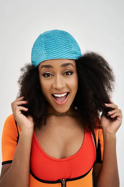 A vibrant young woman smiles while adjusting her unique swimwear, exuding confidence and style. — Stock Photo