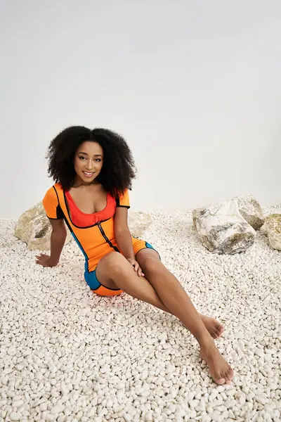 Una mujer joven con estilo se relaja en piedras blancas suaves, exudando confianza. — Stock Photo