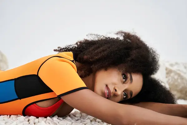 A fashionable young woman relaxes on pebbles, showcasing her unique style and beauty. — Stock Photo