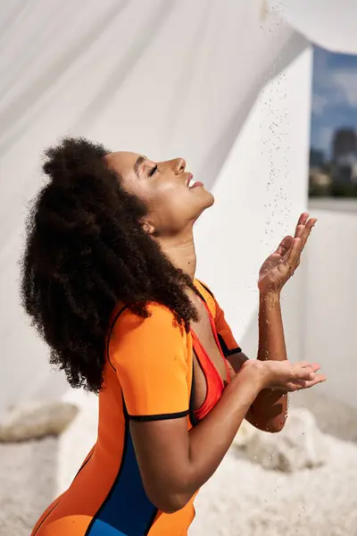 A young woman playfully experiences sand falling through her fingers under the sun. — Stock Photo