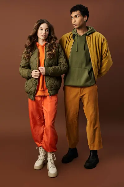 A fashionable couple dressed in bold autumn outfits stands together, exuding style and warmth. — Stock Photo