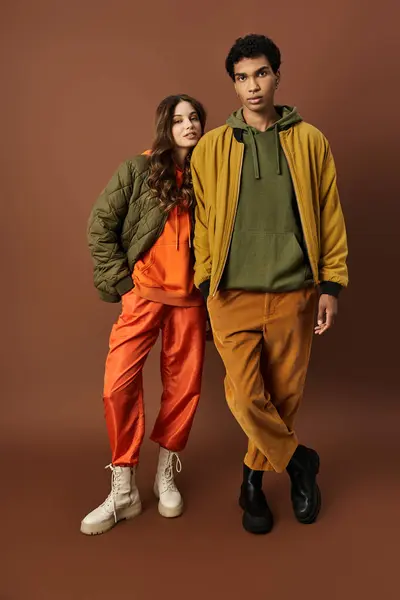 A stylish couple stands confidently in colorful autumn outfits, radiating fashion and warmth. — Stock Photo