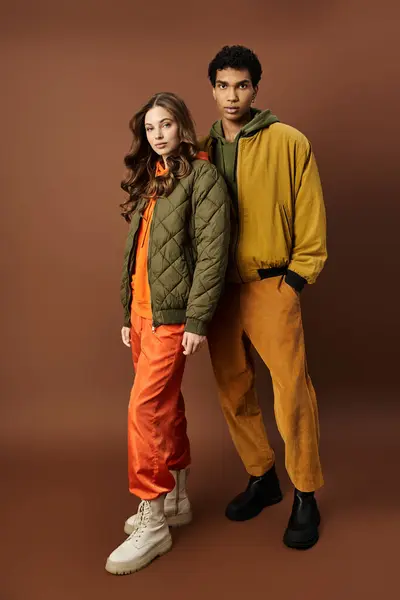 A fashionable couple confidently displays autumn attire in warm, earthy colors, embodying style. — Stock Photo
