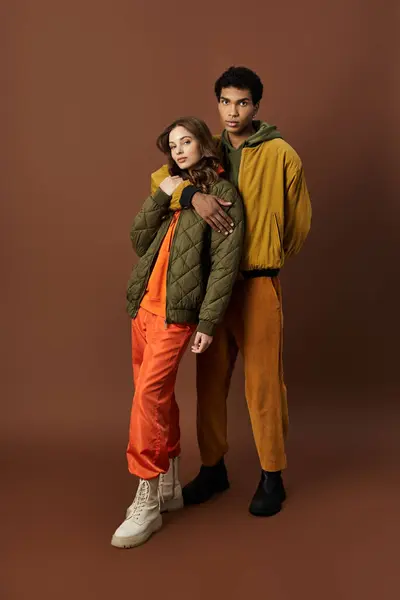 A fashionable couple displays trendy autumn attire in bold colors, exuding confidence and style. — Stock Photo