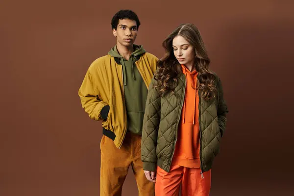 A fashionable couple embraces autumn style with vibrant outfits and playful expressions. — Stock Photo