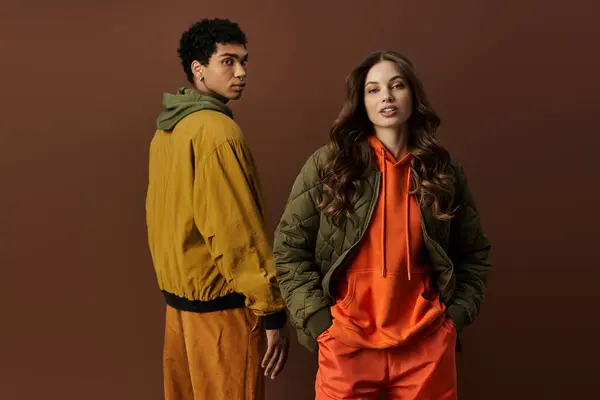 A fashionable pair stands confidently, dressed in rich autumn hues, perfect for the season. — Stock Photo