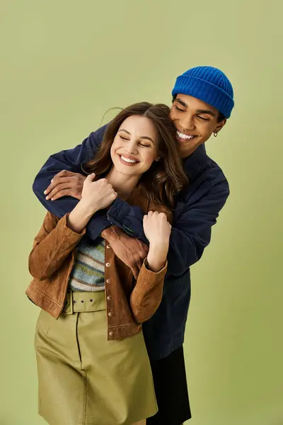 A fashionable couple smiles joyfully in stylish autumn outfits, showcasing playful affection. — Stock Photo