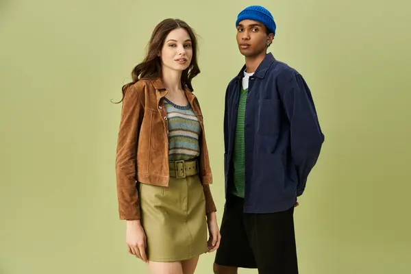 A stylish couple dressed in autumn inspired outfits against a vibrant backdrop captures attention. — Stock Photo