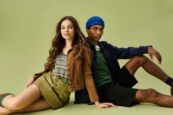 A fashionable couple showcases autumn styles while lounging on the ground, exuding warmth and charm. — Stock Photo