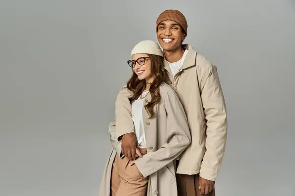 A stylish couple poses playfully, showcasing vibrant autumn attire against a soft background. — Stock Photo