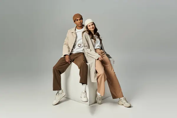 Um jovem casal elegante relaxa em um pedestal, irradiando vibrações de outono com roupas da moda. — Fotografia de Stock