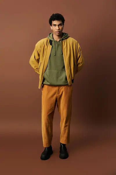 A fashionable young man showcases lively autumn outfits, radiating warmth and style. — Stock Photo