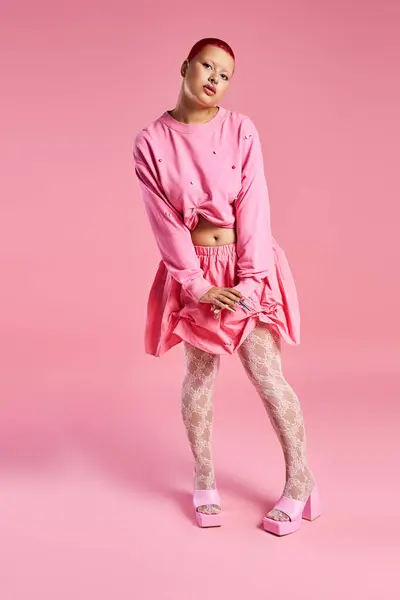 A young woman with short pink hair and a nose piercing displays her daring fashion sense in a colorful studio. — Stock Photo