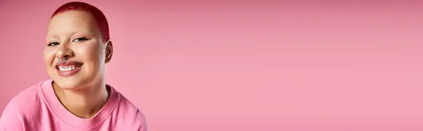 A confident woman with vibrant pink hair and a nose piercing showcases her unique style in a creative space. — Stock Photo