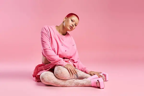 A stylish young woman with pink hair poses confidently in a vibrant pink studio, exuding creativity. — Stock Photo
