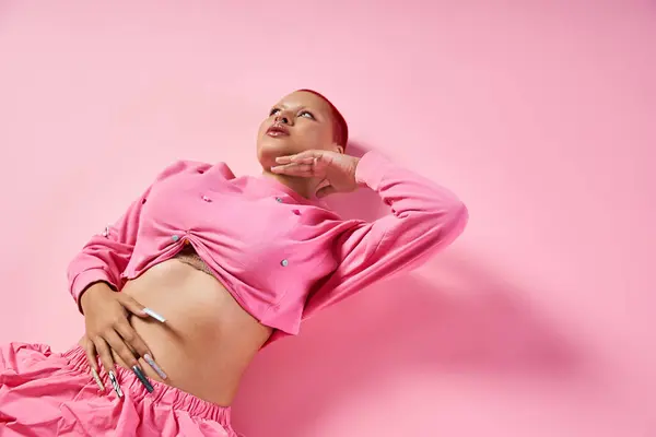 A confident young woman with short pink hair proudly expresses her unique fashion in a colorful studio. — Stock Photo