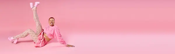 A confident young woman with striking pink hair showcases her unique fashion in a playful studio atmosphere. — Stock Photo