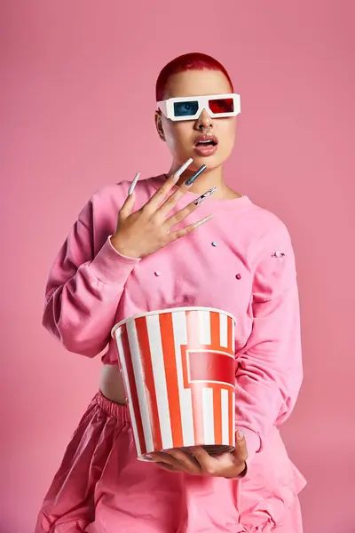 The young woman captivates with her striking pink hair and fashionable outfit, holding a popcorn bucket in hand. — Stock Photo