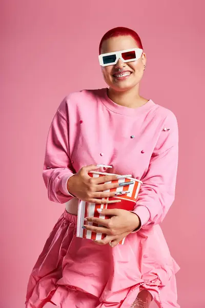A confident young woman showcases her unique style with pink hair and trendy attire while holding snacks. — Stock Photo