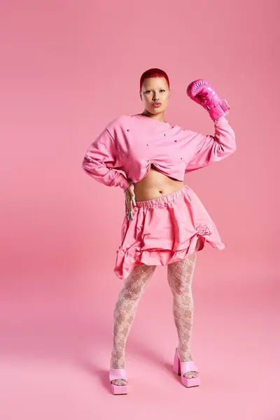 A vibrant studio displays a young woman with short pink hair flaunting her daring fashion choices. — Stock Photo