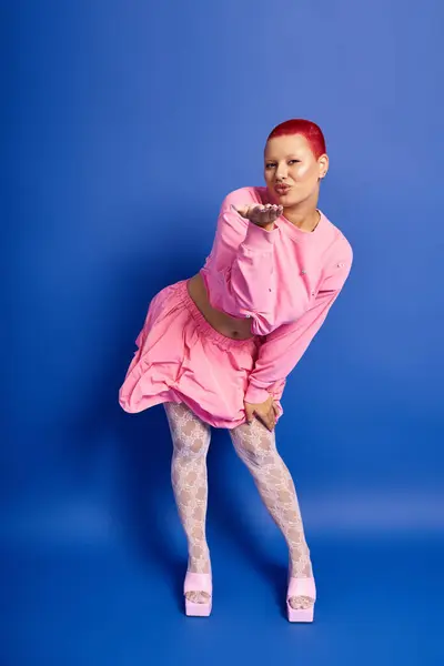 A confident young woman in a pink outfit playfully strikes a pose while showcasing her unique style. — Stock Photo