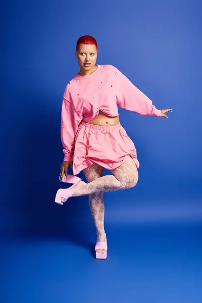 This bold individual with striking pink hair poses playfully, highlighting her daring fashion choices in a studio. — Stock Photo