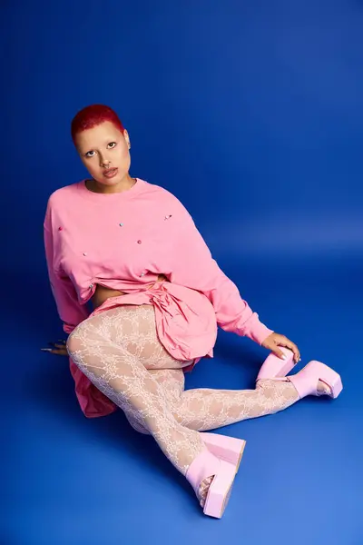 Uma jovem mulher confiante mostra seu estilo único em um estúdio, ostentando cabelo rosa curto e trajes da moda. — Fotografia de Stock