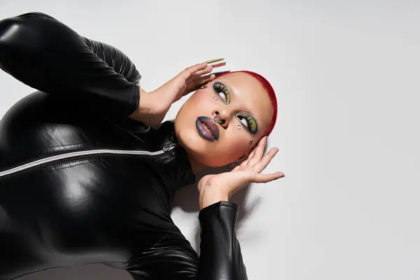 A young woman with short pink hair and bold makeup stands out in a studio, showcasing her unique style. — Stock Photo